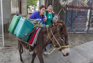 Fabiola Vargas (i) y su madre Delfina Vargas cargan agua potable en su burro para llevarla a su casa en un suburbio de Ciudad de México el 29 de abril de 2014. Foto: AFP Omar Torres escasez de agua en el mundo