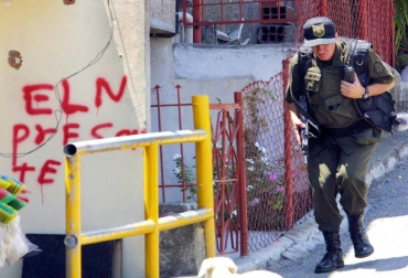 Un policía pasa frente a un letrero del Ejército de Liberación Nacional en Medellín, Colombia, el 14 de octubre de 2002. Foto: AFP. extorsiones colombia farc eln